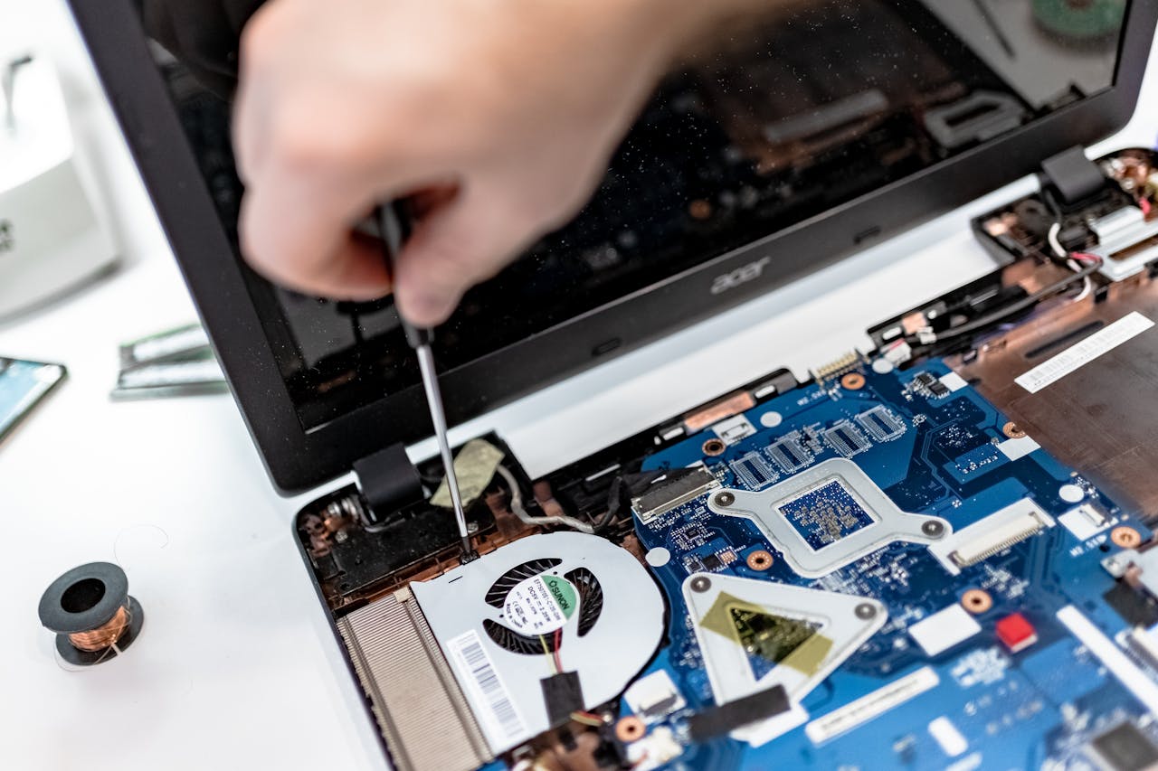 creative-01 Technician repairing a laptop motherboard, focusing on electronic components.